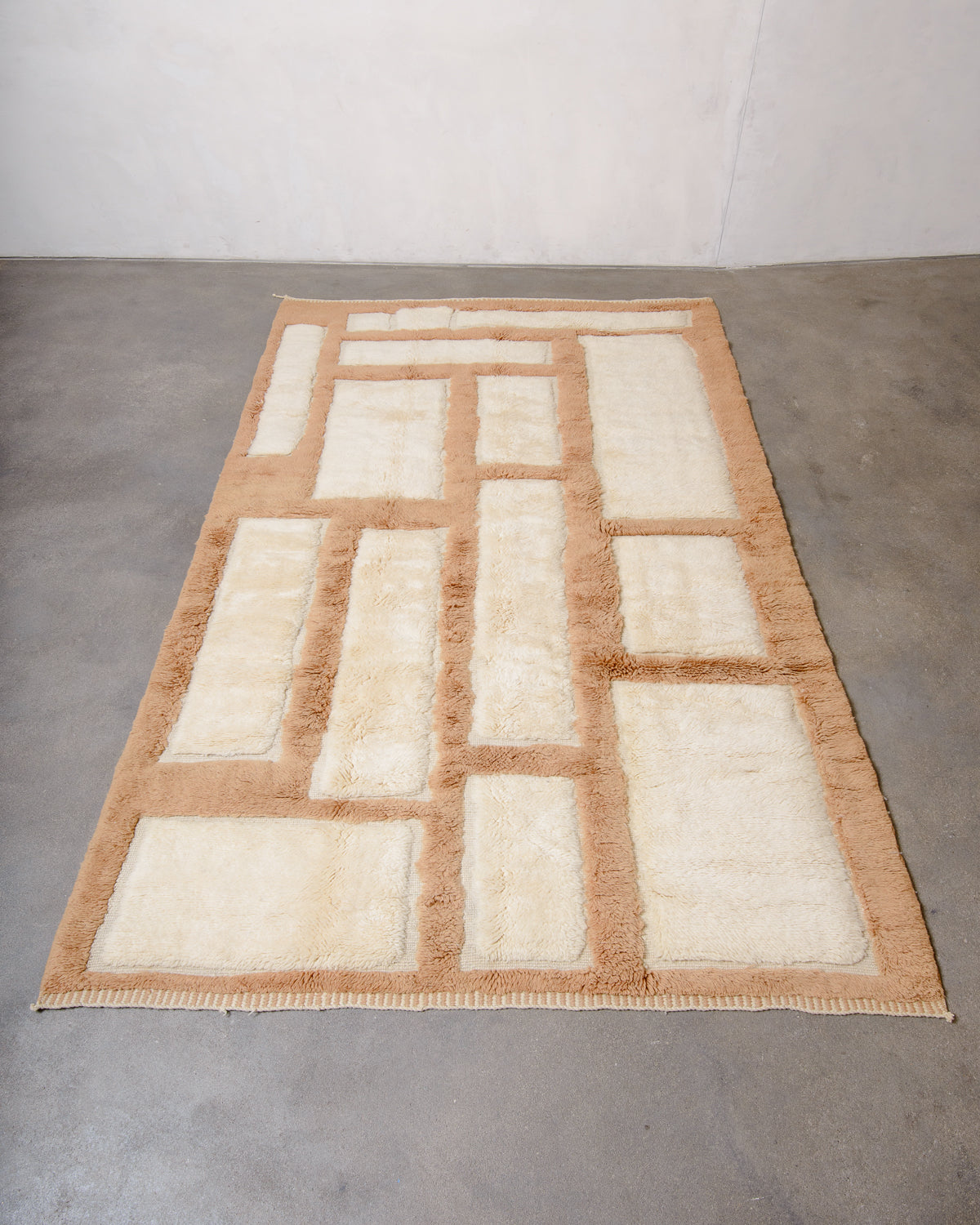 Berberlin Beni M'rirt wool rug in cream and light brown geometric design, laying flat on concrete studio floor.